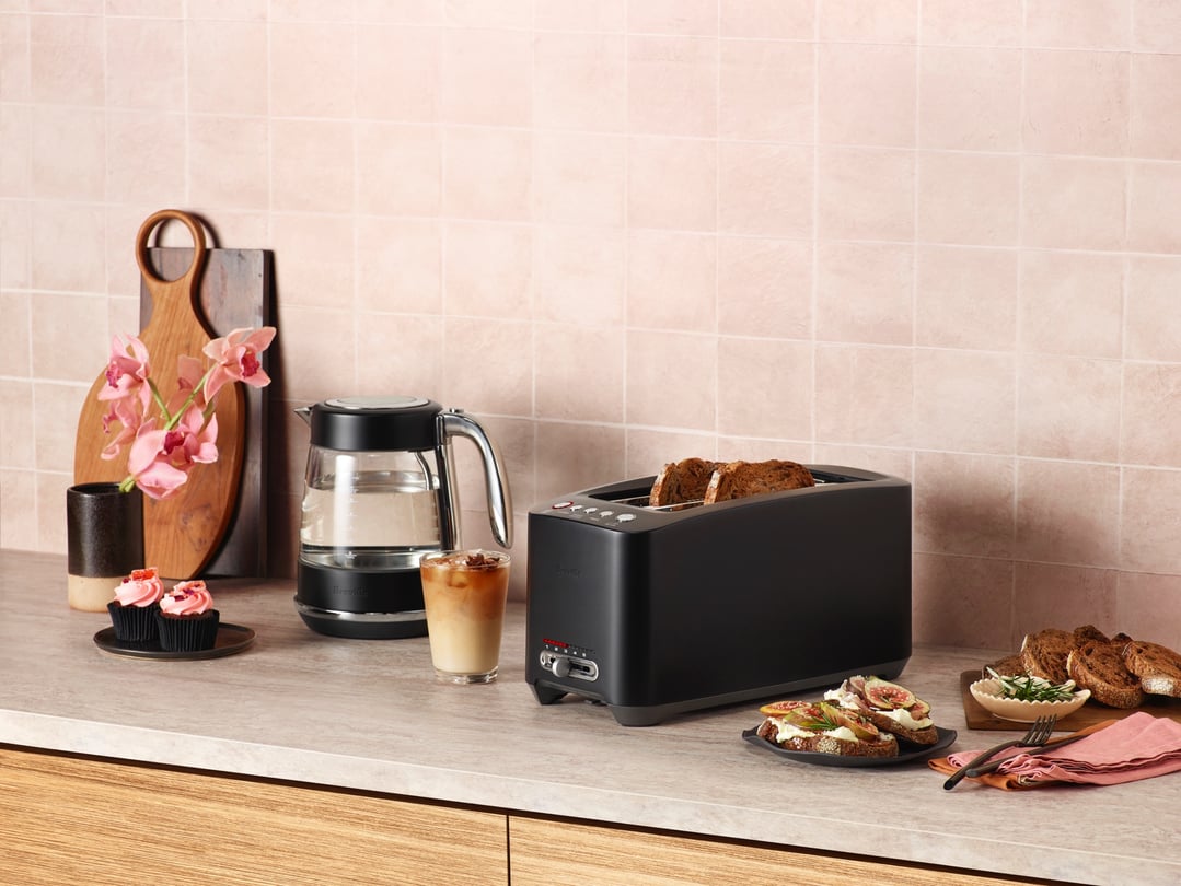 Black Breville toaster on a kitchen counter with food and drinks