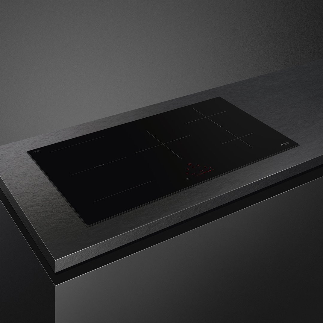 Black induction cooktop built into a dark countertop in a kitchen setting