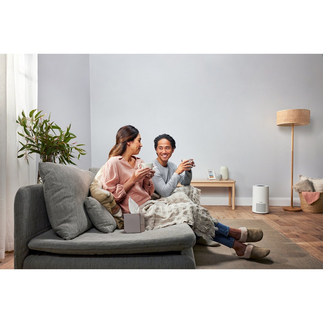 Couple relaxing on a sofa with an air purifier in the living room