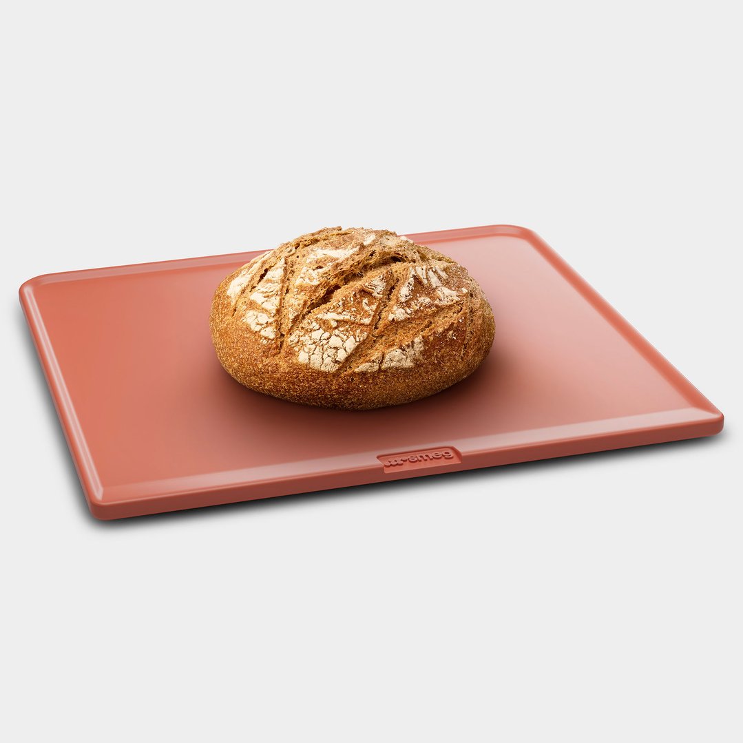 A loaf of bread on a rectangular terracotta-colored refractory stone