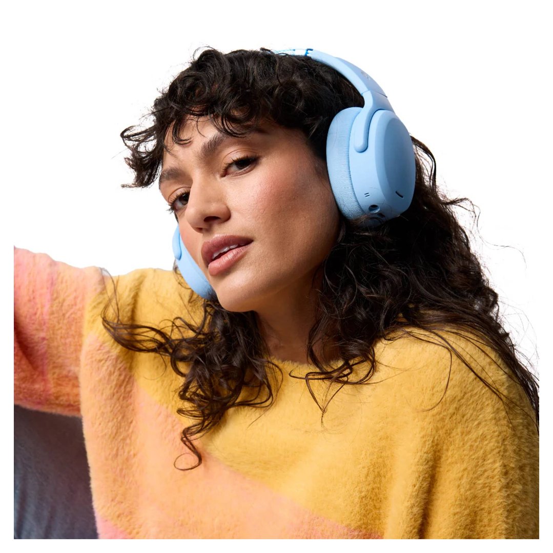 Woman wearing blue Skullcandy Crusher ANC 2 headphones and a yellow sweater