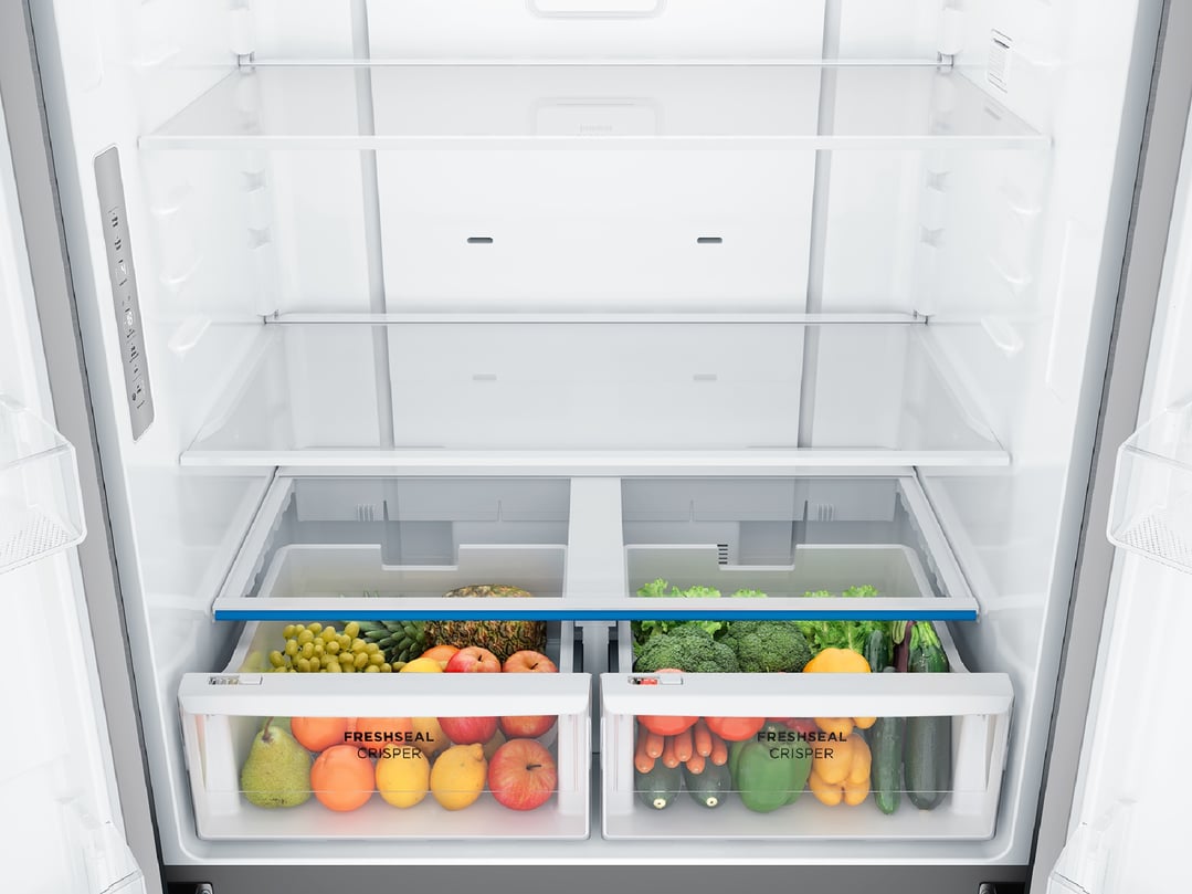 Open fridge interior with fresh fruit and vegetables in crisper drawers