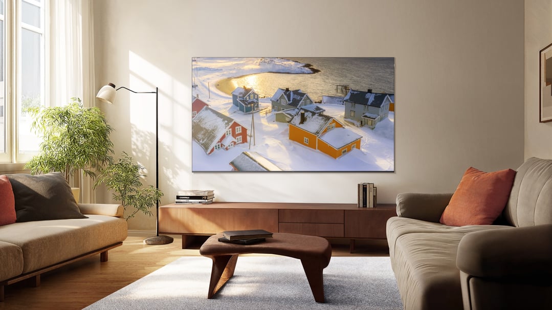 A large QLED Google TV displaying a snowy village scene in a modern living room