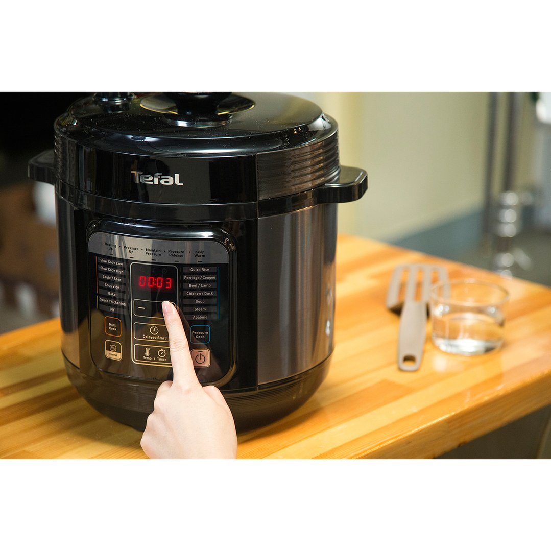 Hand pressing button on a black TEFAL Home Chef Smart Multicooker