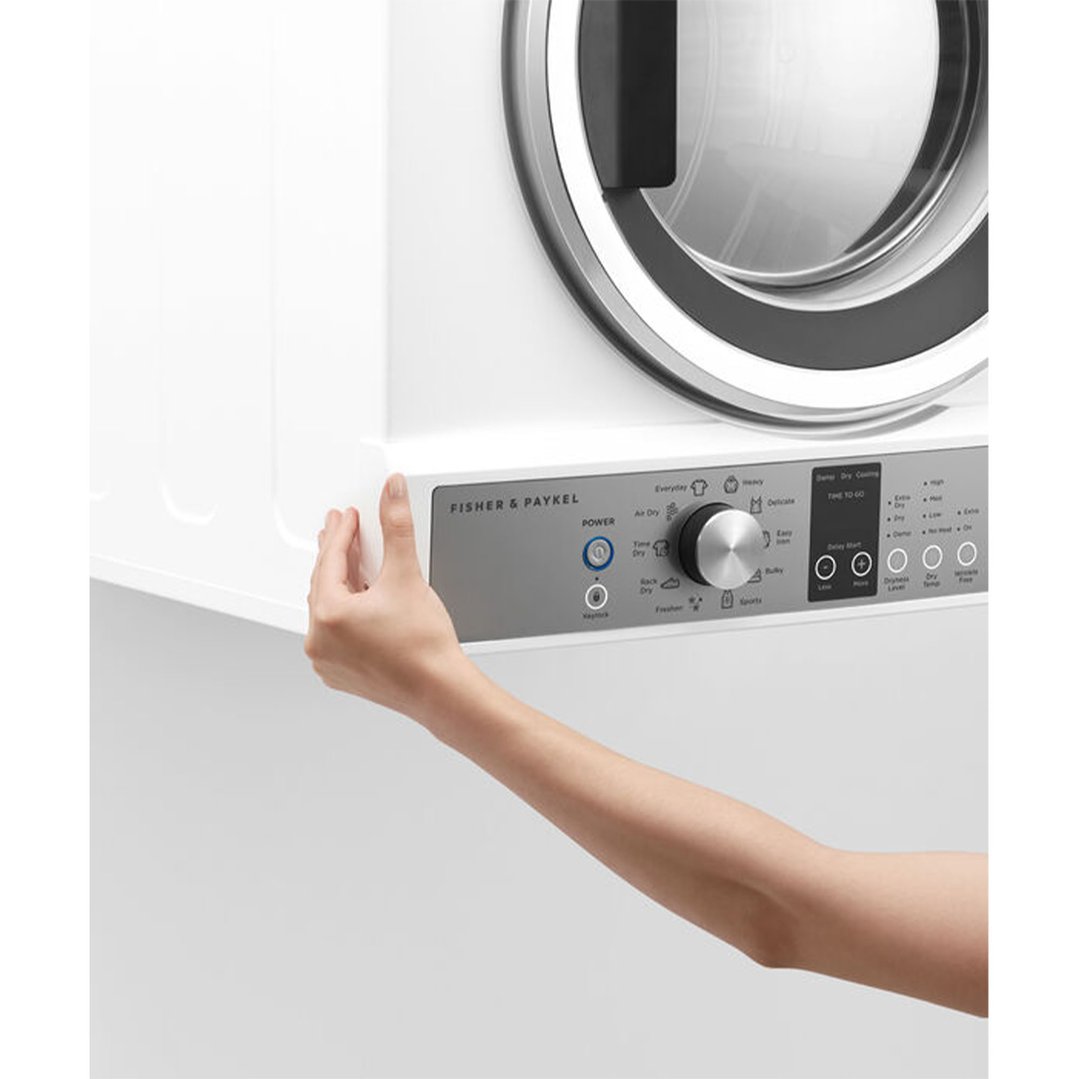 A person's hand adjusting the controls on a white Fisher & Paykel dryer