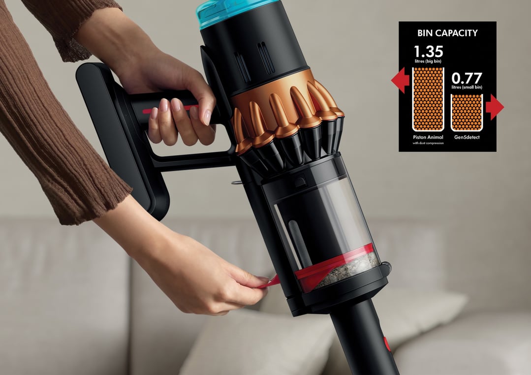 Woman's hands operating a black and copper handStickVacuum, emptying the bin