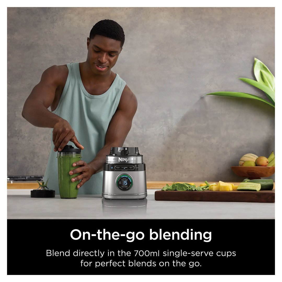 Man blending a green smoothie in a Ninja blender in a kitchen