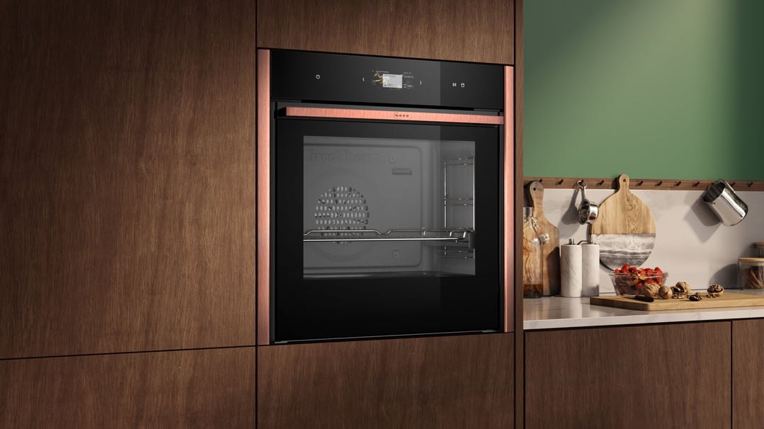 Built-in oven with copper trim in a modern kitchen with wooden cabinetry