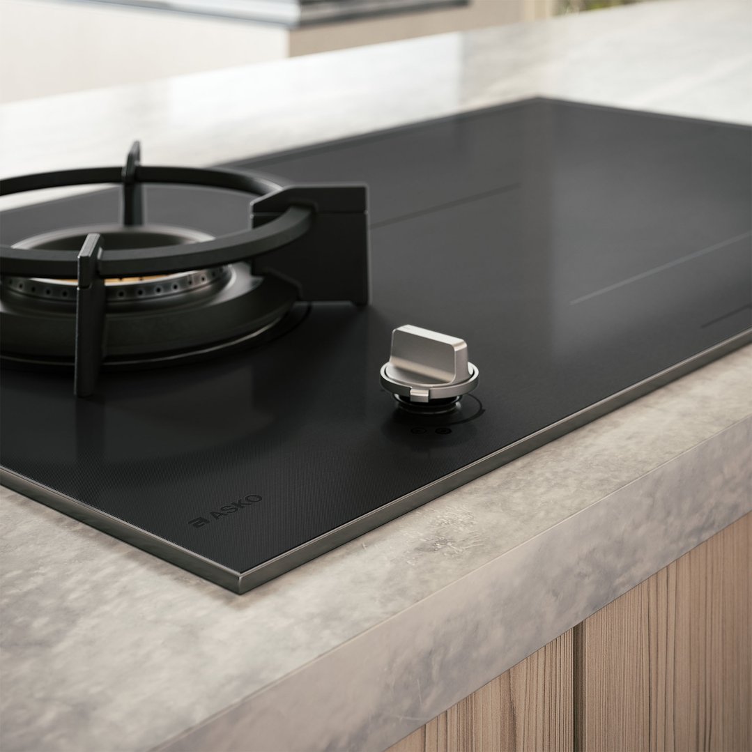 Close up of a black cooktop with gas burner and induction zones