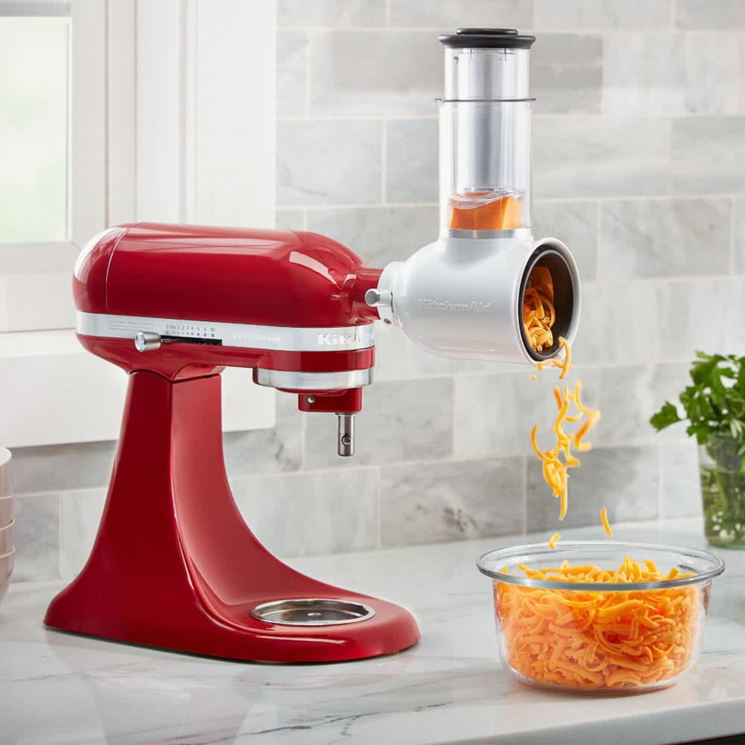 Red stand mixer with Fresh Prep Slicer/Shredder Attachment shredding cheese into a bowl